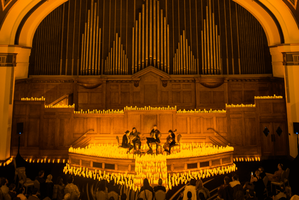 A string quartet performing on a stage surrounded by candles at the Lotte Hotel.