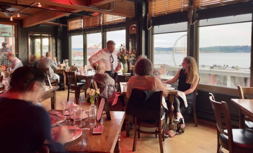 Waterfront views with customers and server at Maximilien Restaurant in Seattle